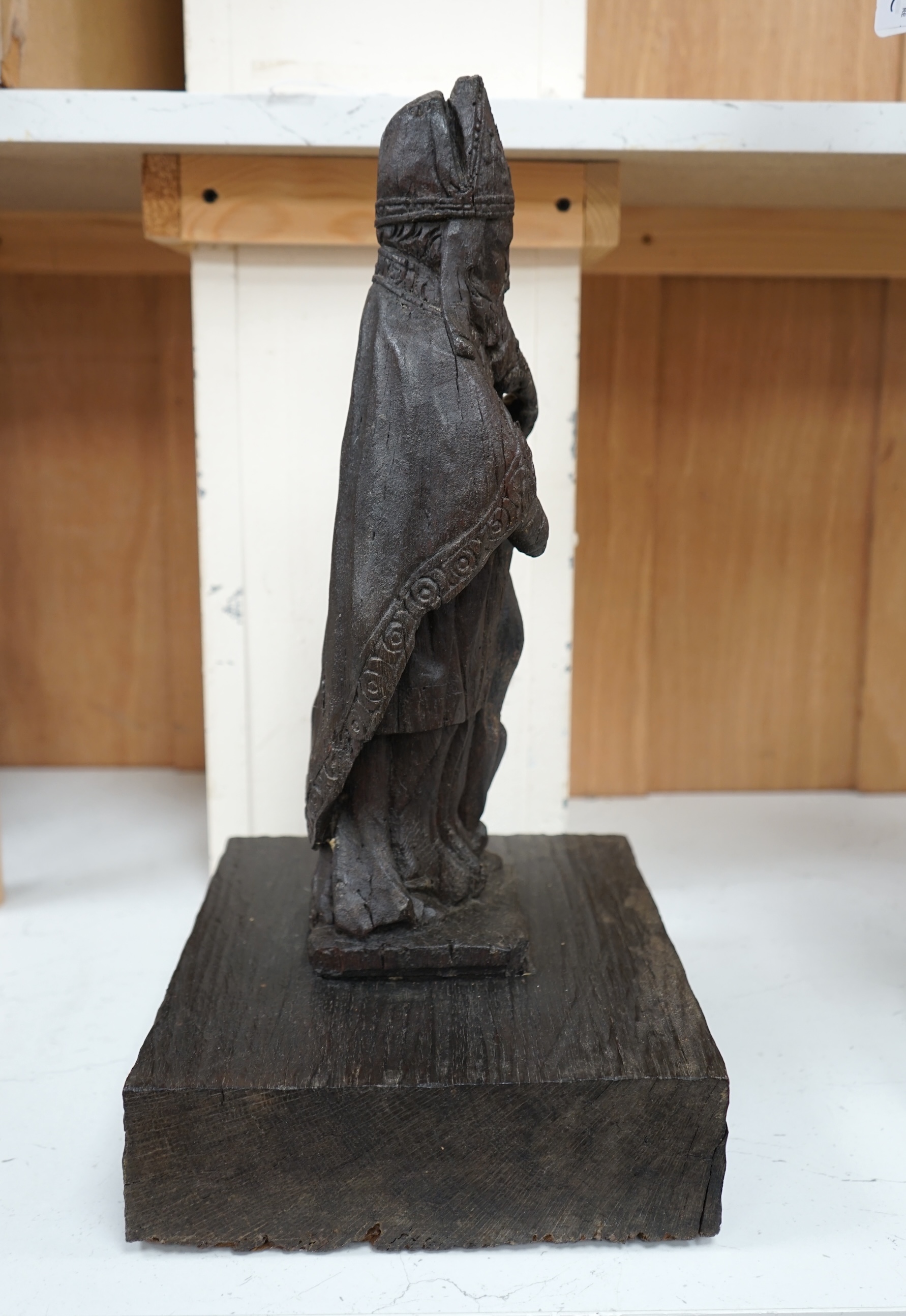 A North European oak carving of a bishop, possibly 17th/18th century, 38cm high not including stand. Condition - poor